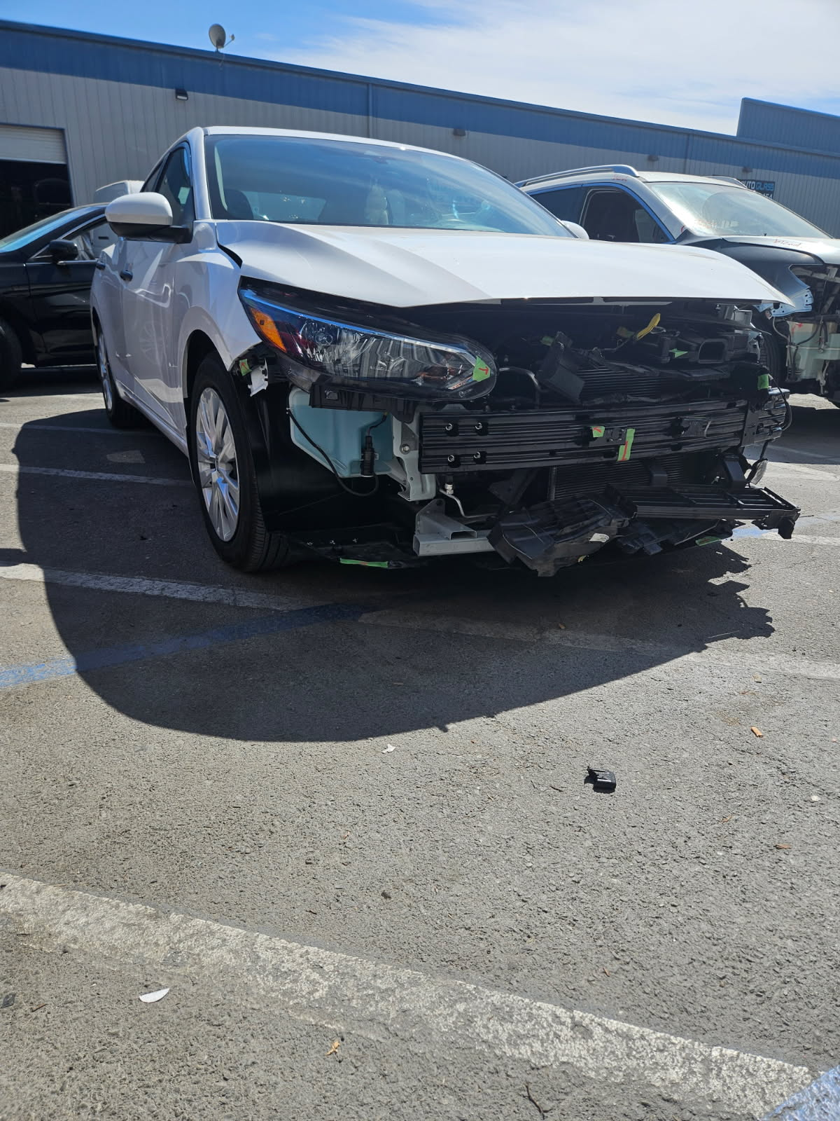 White Nissan with front end collision damage before repair